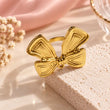 18K gold plated bow ring for women styled on cream stone with pink background – TVAYI