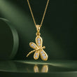 A gold dragonfly pendant necklace adorned with small clear stones, hanging from a delicate gold chain against a dark green background. – Aurelia Dragonfly Lab-Grown Diamond Pendant