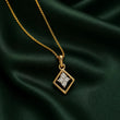 A gold chain necklace with a diamond-shaped pendant featuring a clear crystal star in the center, displayed on a draped dark green satin fabric. – Geometric Spark Diamond Pendant Necklace