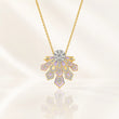 A gold pendant necklace featuring a geometric, fan-shaped design with light purple enamel inlays and clear stones, suspended from a delicate gold chain against a soft, light beige background. – Lavender Cascade Lab-Grown Diamond Necklace