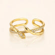 A gold-plated open ring band featuring two leaf-shaped ends, with pavé-set clear crystals along the top curve, photographed on a light cream background. – Serpentine Spark Adjustable Ring